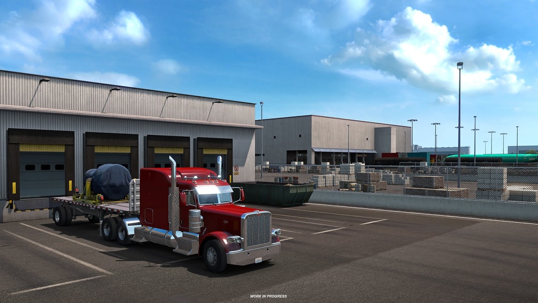 En röd lastbil med flak lastad med en stor flygplanskomponent parkerad vid en lastkaj på en logistikanläggning.